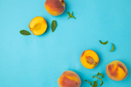Ripe red peaches with mint leaves isolated on bright blue background with copy space for your text. Top view. Flat lay patternの写真素材
