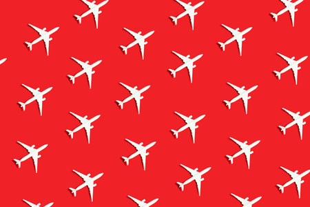 Creative composition with passenger plane pattern on red background. Summer travel or vacationの写真素材