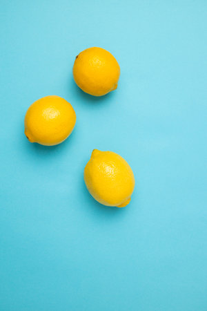 Ripe yellow lemons on blue background with copy space for your text. Top view. Flat lay pattern, banner. Frame made of fresh lemonsの写真素材