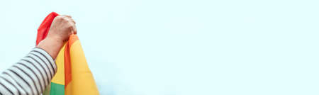 Person hand with a colorful rainbow flag on blue background. LGBT equal rights movement and gender equality conceptの写真素材