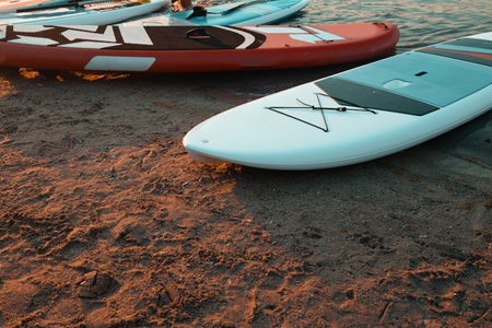 Three sup boards lying near the water on sea on the sunset. Healthy lifestyle.の写真素材