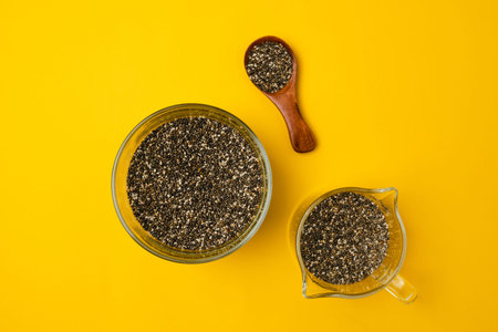 Glass bowl and spoon with chia seed son a bright yellow background, closeup, view from aboveの写真素材