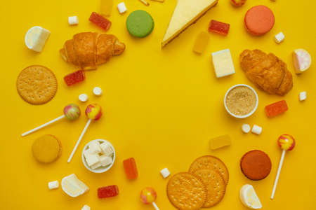 Assorted delicious bright sweets, jelly and cookies frame on a bright yellow background. Top view with copy spaceの写真素材