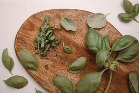 Fresh basil leaves on wooden cutting board isolated on white background.の写真素材