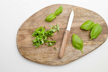 Fresh organic green basil herbs with a knife on wooden board background for cooking.の写真素材