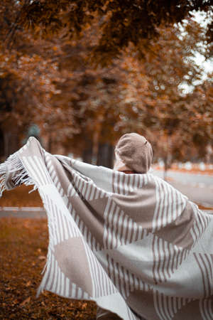 Fall season. Caucasian happy lady in warm casual clothes and a cozy scarf dancing and spinning in the autumn parkの写真素材