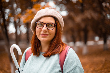 Woman walking with transparent umbrella under rain at autumn park
