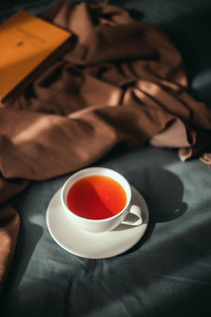 Hot black tea in a cup on a gray cozy bed in a morning autumn day.の写真素材
