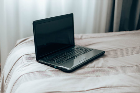 Working online from home. Laptop with blank black screen on cozy bed, copy space. Shopping online...