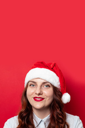 Christmas and New Year holiday background. Beautiful caucasian girl with makeup and red santa hat on...