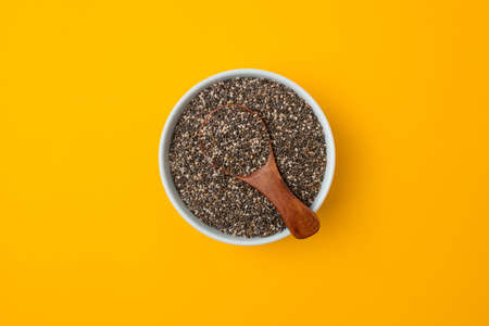Glass bowl and spoon with chia seed son a bright yellow background with copy space, closeupの写真素材