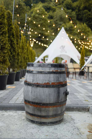 A wooden old barrel outdoor in street cafe. Green thuja in flowerpot in the streetの写真素材
