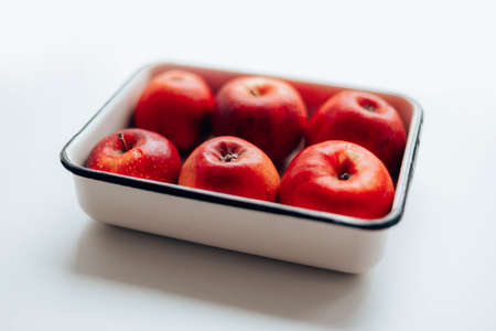 Tasty juicy red ripe apples in a metal enamel container on the table. Autumn composition.の写真素材