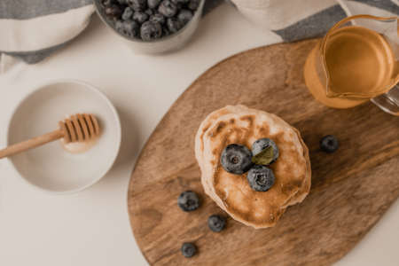 Delicious pancakes with fresh blueberries and honey syrup on a gray table on a light background, copy space. Top view, flat layの写真素材