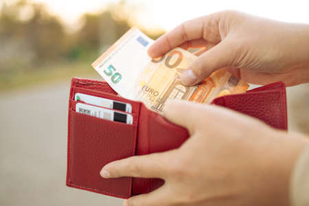 Close up of business style female hands holding a red leather wallet with 50 euro banknotesの写真素材