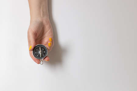 Close-up female hand holding a travel compass on a grey background. Copy space for text or designの写真素材