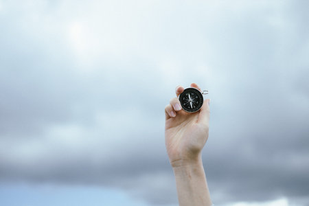 Traveler hand holds compass against beautiful Carpathian mountains view. Horizontal banner with...