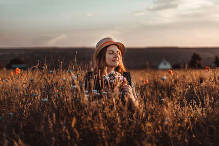 Beautiful smile young caucasian girl in a dress enjoys the sunset in the field. Tourism, traveling and healthy lifestyle concept.の写真素材