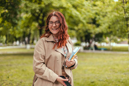 Portrait of a young attractive student girl poses looking at camera in the street. Back to school concept photoの写真素材