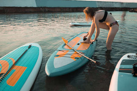 Athletic woman paddling on a SUP sits paddle board in blue water seaの写真素材
