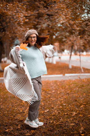 Beautiful happy stylish woman having fun spinning in circles while walking autumn forestの写真素材
