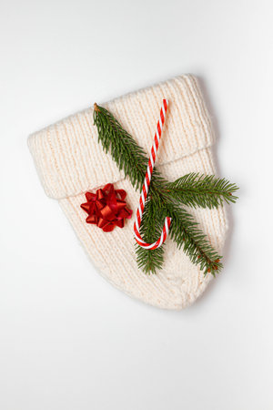 White knitted hat, pine branch and sweet candy cane decor on a white background. Christmas, winter, new year concept. Flat lay, top viewの写真素材