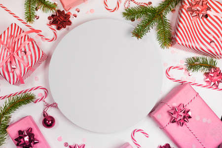 Christmas composition. Circle frame, pine tree branches, christmas gift boxes decorations on colored background. Top view, copy space for textの写真素材