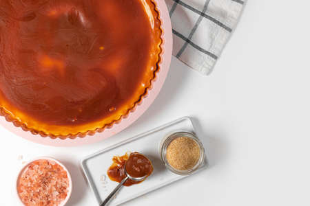 Classic cheesecake with caramel sauce on white plate on white background. Copy space for text.の写真素材