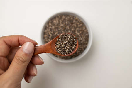 Chia seeds in wooden spoon and cup from top view with space on white backgroundの写真素材