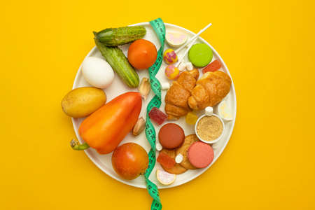 Harmful sugar and healthy food on a yellow background. Diet opposition concept,close-up top viewの写真素材