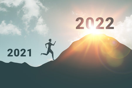 Silhouette of active man running to the top of the mountain with new year 2022 and let 2021 behind conceptの写真素材