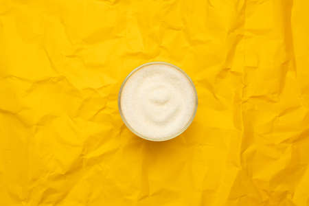 Sugar in glass bowl on a yellow background. Diabetes and unhealthy diet concept. Top view, flat lay, copy space.の写真素材