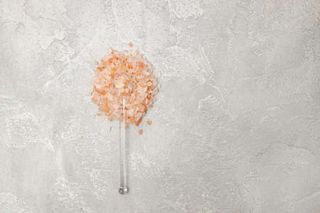 Pink himalayan salt with glass spoon on gray background. Top view, flat lay, copy space.の写真素材