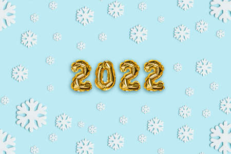 2022 gold foil balloons with snow decor and Christmas snow with copy space on blue background. New Year and Xmas conceptの写真素材