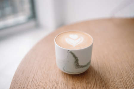 Cappuccino coffee in ceramic mug on wooden table at modern style cafeの写真素材