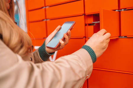 Woman client using automated self service post terminal machine or locker. Mail shipping conceptの写真素材