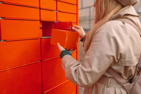 Putting carton box with shipping goods to self service postal case. Mail shipping conceptの写真素材