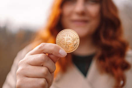 Golden bitcoin in a business woman hand outdoors. Cryptocurrency concept, investing in crypto assets, blockchain and altcoinsの写真素材