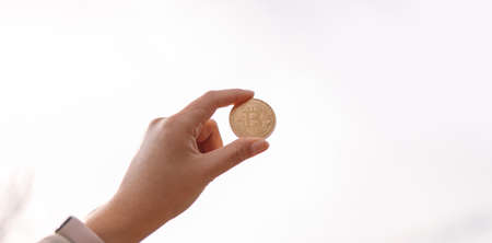 Unrecognizable female hand showing bitcoin cash coin with copy space on a sky backgroundの写真素材