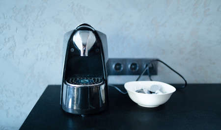 Modern professional espresso capsule coffee maker, cup on kitchen table. Having breakfast in the morningの写真素材