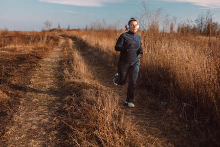 Sportive young woman runs in the park and listens to music. Sports lifestyle.の写真素材