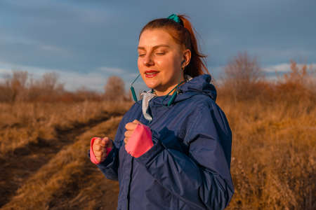 Happy sportive woman listening to music on headphones while jogging in nature in the morning. Healthy lifestyle concept. Active sports peopleの写真素材