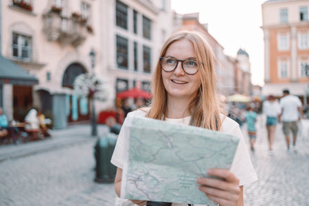 Happy young woman using a city map on a city street, traveling in Europe, freedom and active...