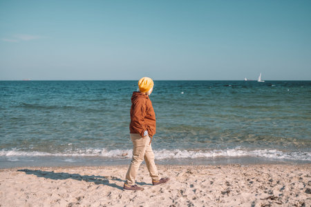 Image of happy 50s woman relaxing on the sandy beach against the sea