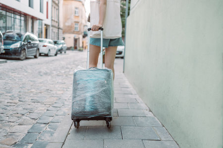 Young blonde female traveler walking with a suitcase outdoors at a urban city. Tourism concept. Waiting for taxiの写真素材