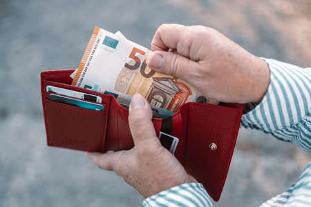Close up of business style female hands holding a red leather wallet with 50 euro banknotesの写真素材