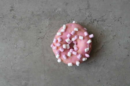 Pink donut on gray concrete background. Healthy and unhealthy foods. Healthy lifestyle, food and sport conceptの写真素材