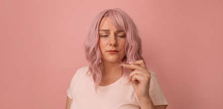 Portrait of upset unfortunate young woman hand holding dry damaged hair problemの写真素材