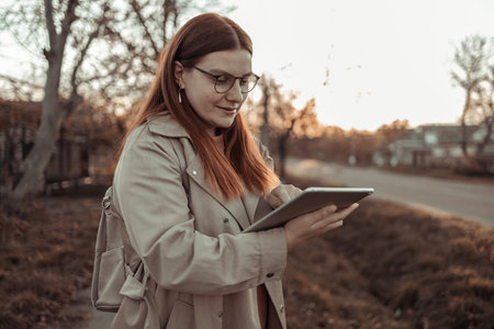 Happy woman using tablet pc, online shopping while standing in the park.
