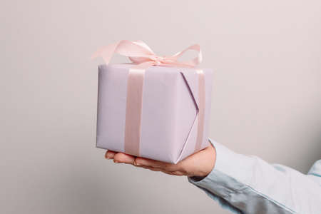 Close up shot of woman hands holding gift package box on pink pastel background with copy space.の写真素材